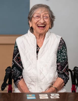 Smiling elderly woman sitting at a table with cards