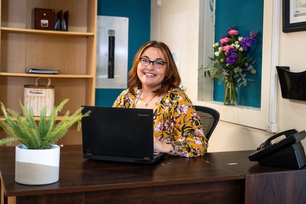 Staff member at a reception desk with flowers in the background