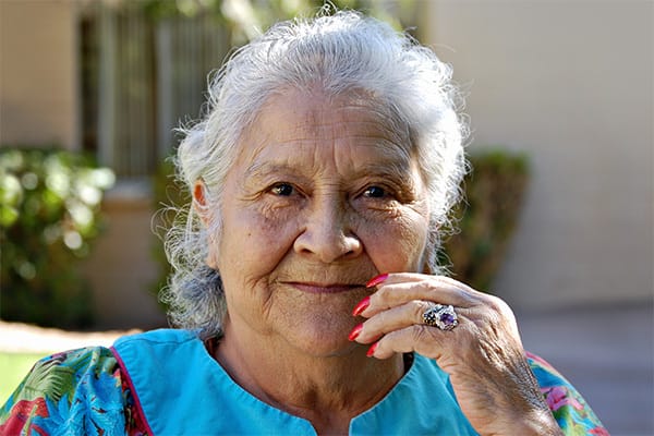 Smiling elderly woman with colorful attire outdoors