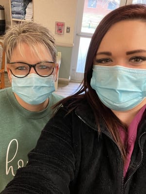 Two staff members wearing masks in an interior setting