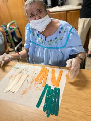 Senior resident engaging in a craft activity with colorful materials