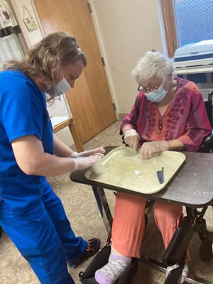 Staff member assisting a resident with a craft activity
