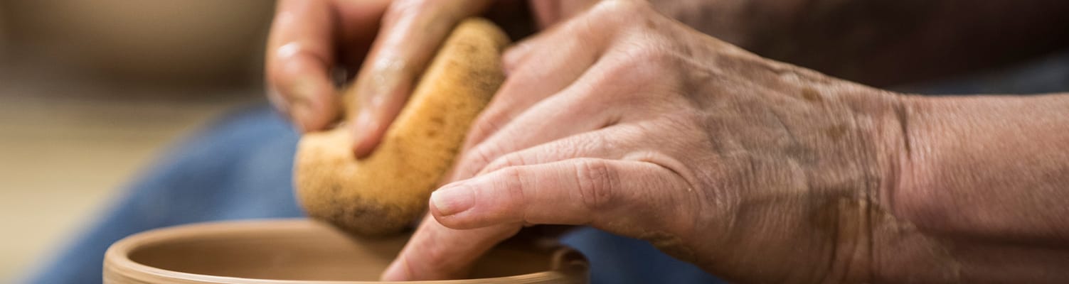 Close-up of hands molding clay in a pottery activity
