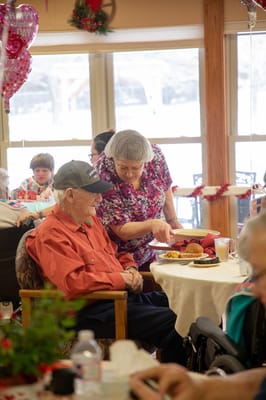 Staff assisting resident during a meal in a dining area