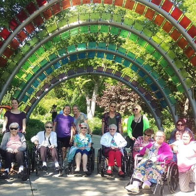 Residents posing together under a colorful outdoor arch