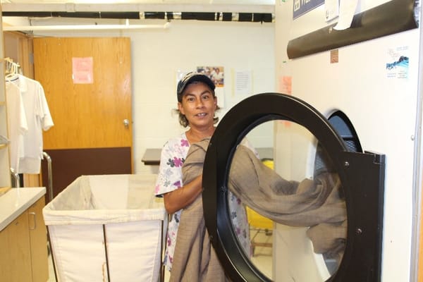 Staff member using a commercial dryer in the laundry room