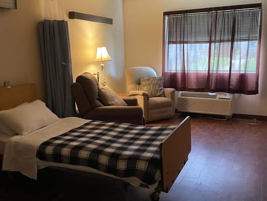 A private resident room with a bed and seating area