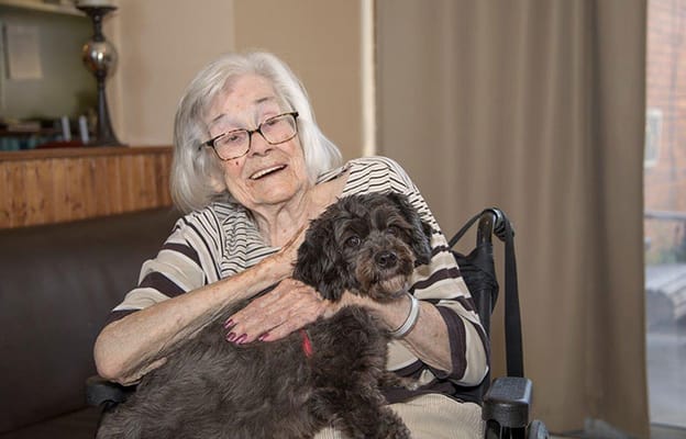 Elderly woman smiling with a small dog on her lap