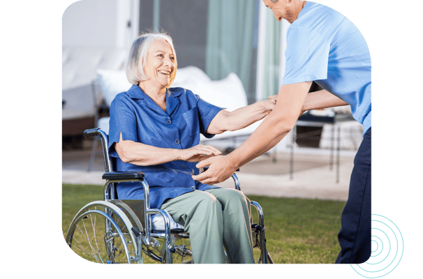Caregiver assisting a resident in a wheelchair outdoors