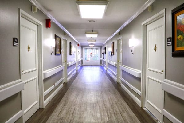 Well-lit hallway with doors and artwork