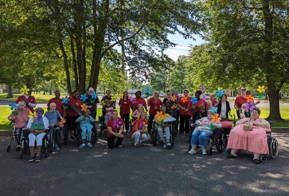 Residents and staff participating in an outdoor activity with colorful flowers