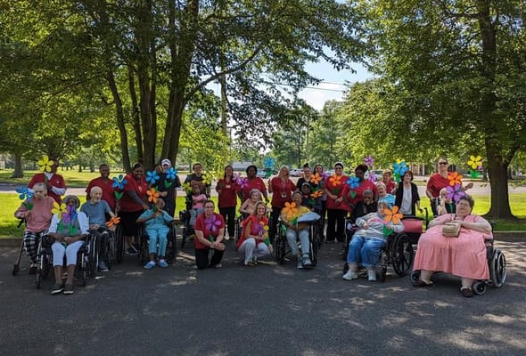 Residents and staff participating in an outdoor activity with colorful flowers