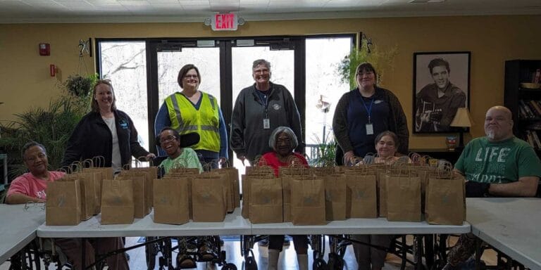 Residents and staff posing with gift bags in a common area