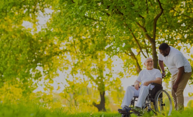 A resident in a wheelchair enjoying time outdoors with a staff member