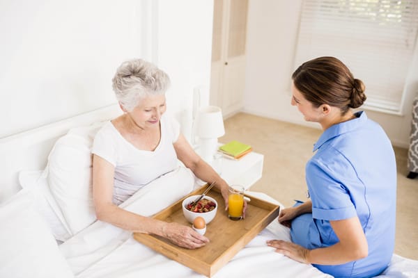 A caregiver serving a meal to a senior resident
