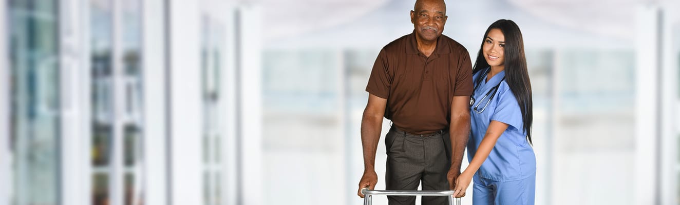 A senior man with a caregiver in a facility hallway