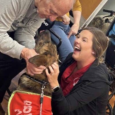 A staff member interacting with a resident and a dog