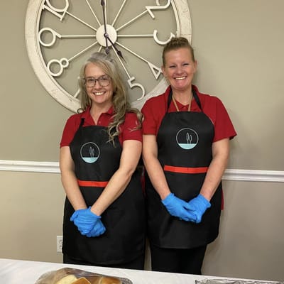 Two staff members preparing food in a dining area