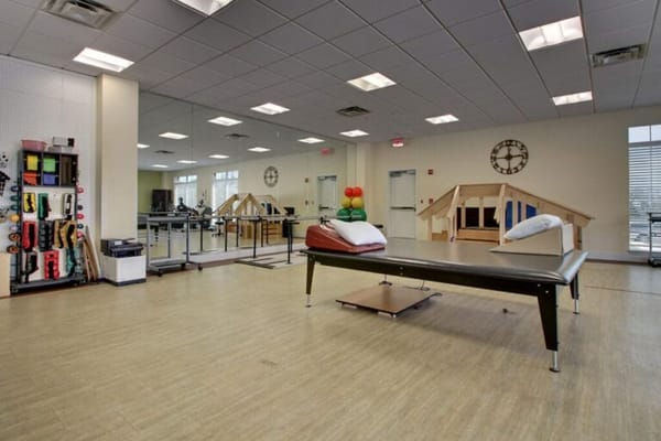 A bright therapy room with equipment and exercise areas