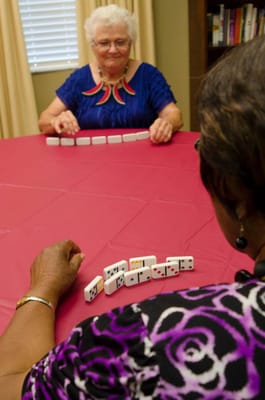 Two residents enjoying a game of dominoes at a table