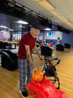 Resident bowling with a walker in an activity room