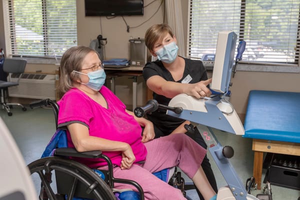 Staff assisting resident with therapy equipment