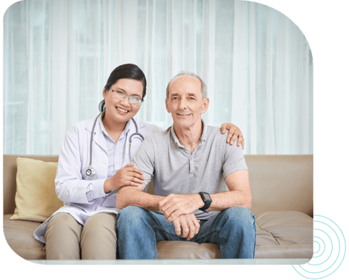 Nurse and senior patient smiling together on a couch