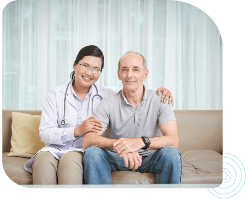Nurse and senior patient smiling together on a couch