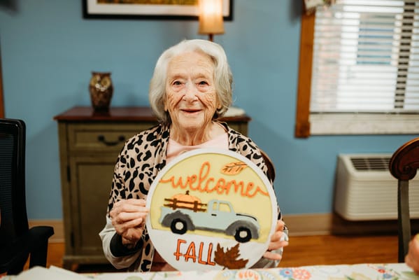 Resident smiling while holding a fall-themed sign