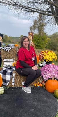 Staff member posing at a fall-themed outdoor display