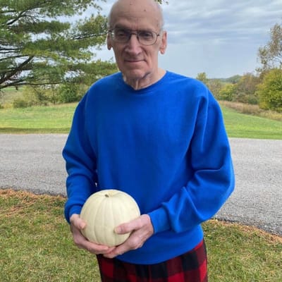 Resident holding a pumpkin in an outdoor setting
