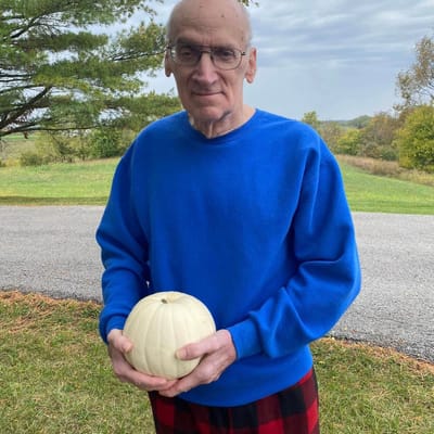 Resident holding a pumpkin in an outdoor setting