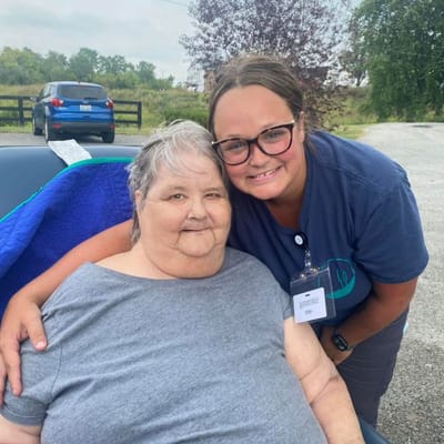 A resident and staff member smiling outdoors