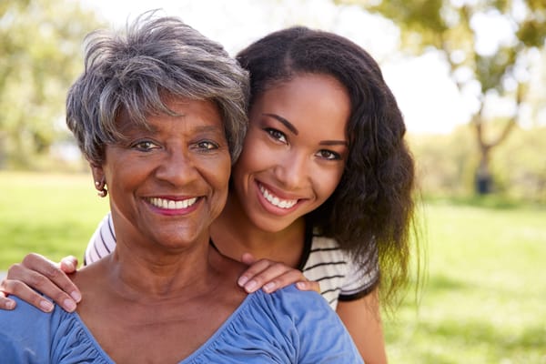 Smiling senior woman and caregiver outdoors in a park