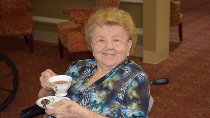 Resident enjoying tea in a cozy lounge area