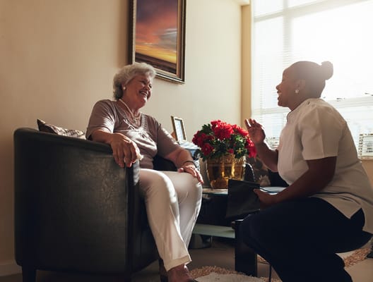 Resident enjoying a conversation with staff in a cozy room