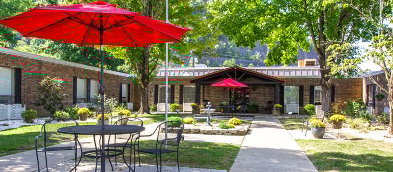 Outdoor seating area with red umbrellas and greenery