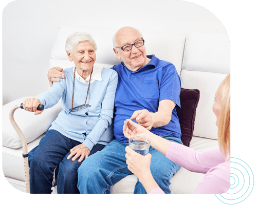 Elderly couple receiving medication from a caregiver