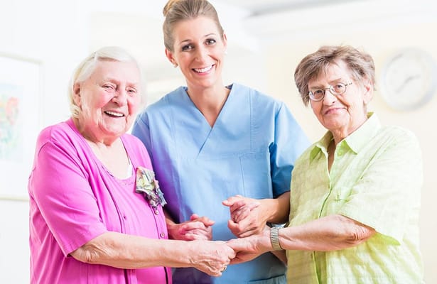 Staff member assisting two elderly residents