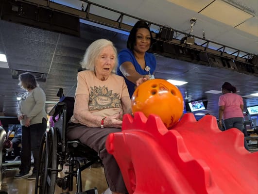 Residents enjoying a bowling activity with staff assistance