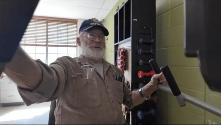 Senior man exercising with weights in a fitness room