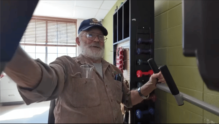 Senior man exercising with weights in a fitness room