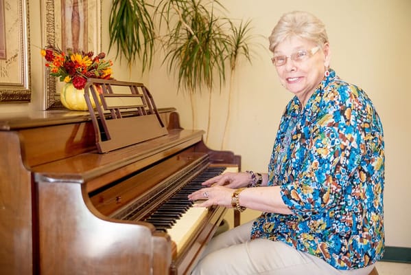 Resident playing piano in a bright room