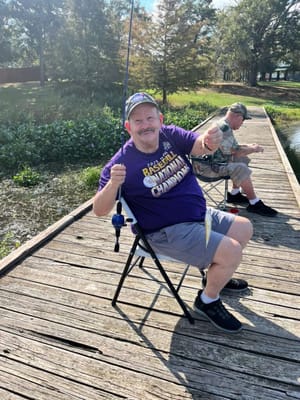 Resident fishing by a pond with another person visible