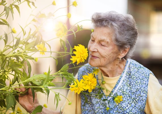 Elderly woman enjoying flowers in a garden