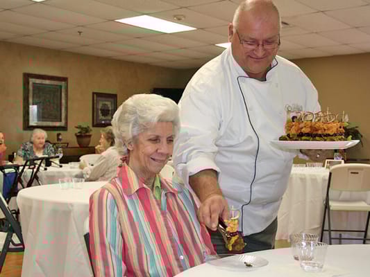Chef serving food to a resident in a dining area