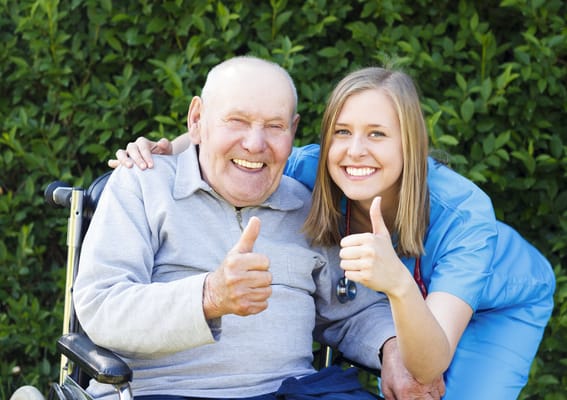 Senior resident and caregiver giving thumbs up outdoors