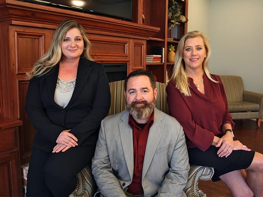 Three staff members posing in a welcoming lounge area