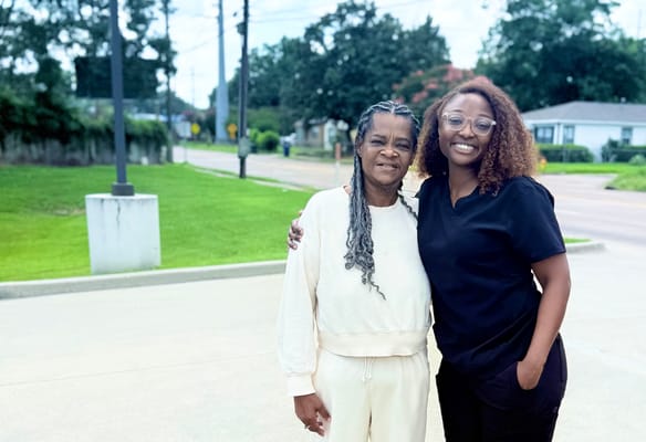 Two smiling women outdoors, representing staff and resident