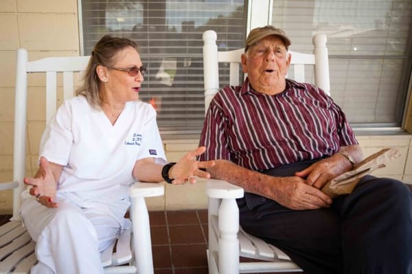 A caregiver and resident engaging in conversation on a porch
